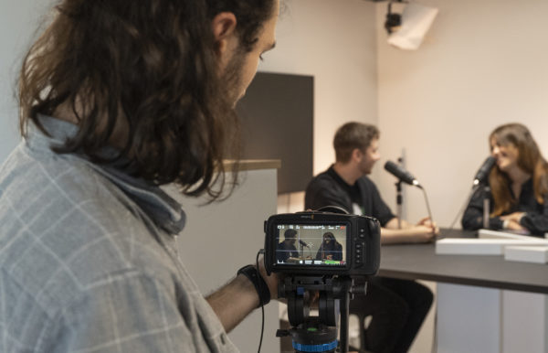 Un collaborateur filme l'enregistrement d'un podcast sur l'audit RH et l'expérience candidat entre deux personnes dans les studios