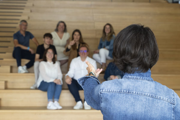 Une femme de dos s'adressant à une audience dans l'amphithéâtre de l'agence We Feel Good