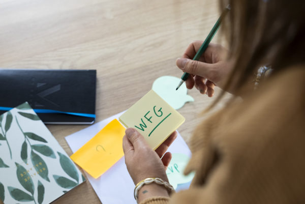 Vue de haut d'une personne écrivant We Feel Good en abrégé sur un post It