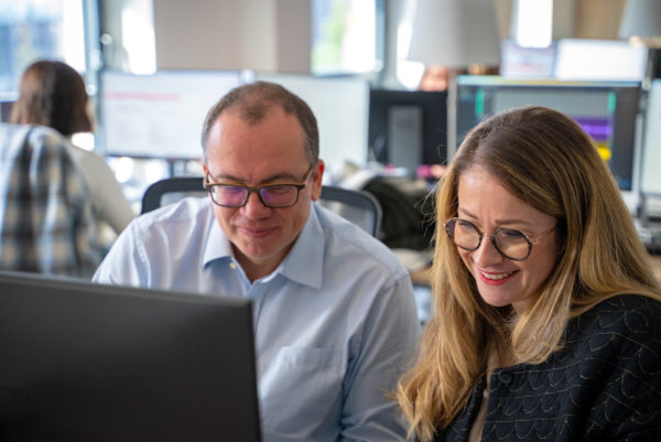 Deux collaborateurs regardent un écran dans les bureaux We Feel Good