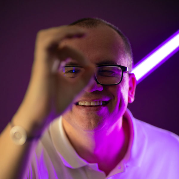 Portrait d'un membre de l'équipe We Feel Good avec un fond violet et néon