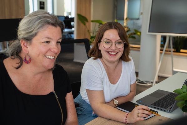 Deux collaboratrices travaillent sur leur ordinateurs dans les bureaux de l'agence We Feel Good