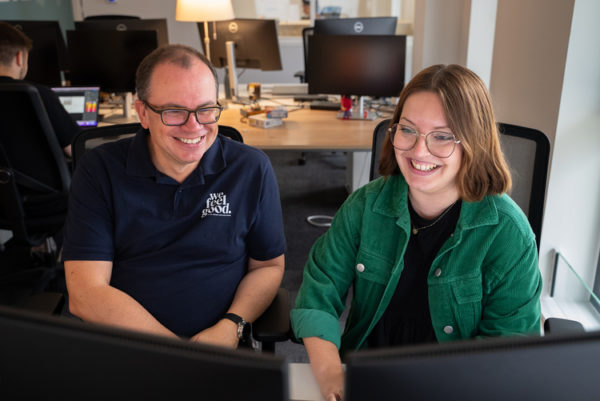 Le fondateur et une collaboratrice devant deux écran d'ordinateur dans les bureaux de l'agence We Feel Good