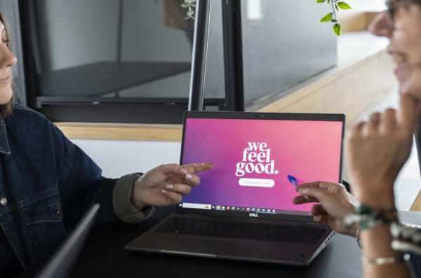 Deux personnes pointent du doigt l'écran d'un ordinateur avec le logo de la marque We Feel Good